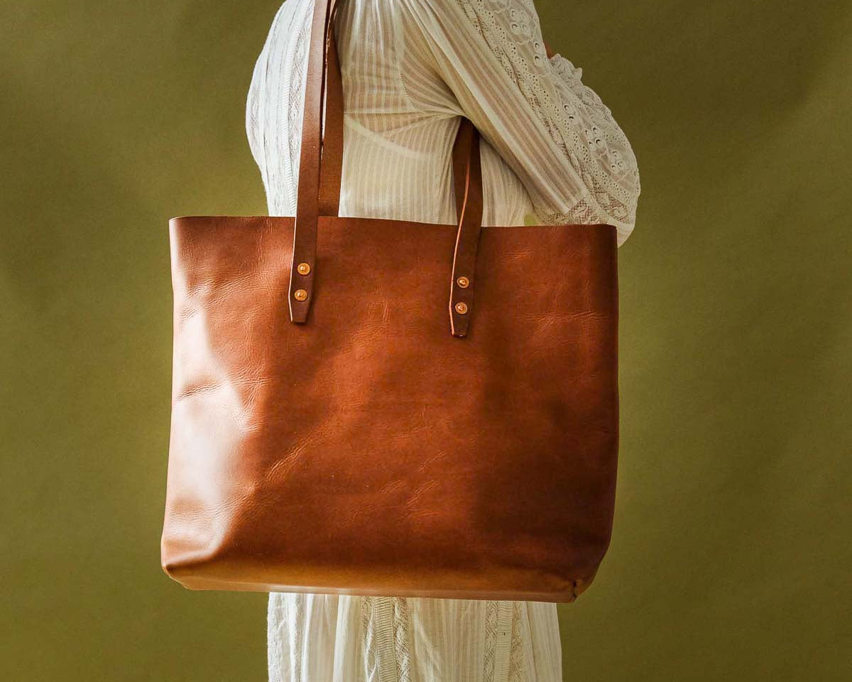 Woman wearing a white dress carrying WP Standard vintage brown full-grain leather tote bag.
