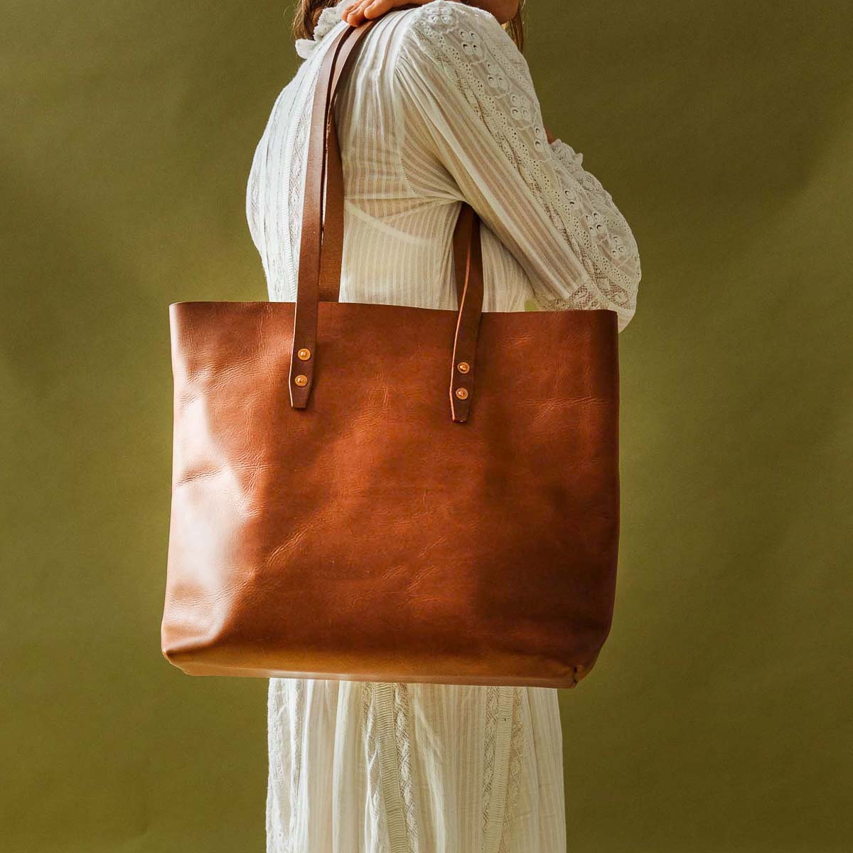 Woman wearing a white dress carrying WP Standard vintage brown full-grain leather tote bag.