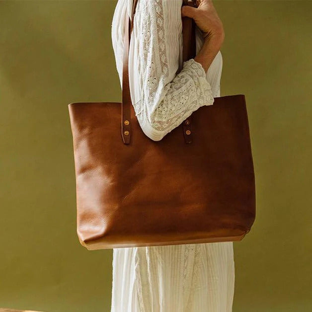 A woman holding a brown leather tote bag