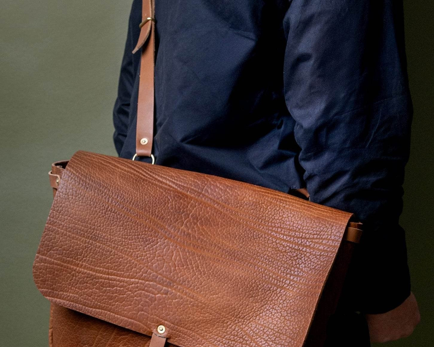  A Leather Messenger Bag from WP Standard with a long, luxurious strap on the shoulder of a model. 
