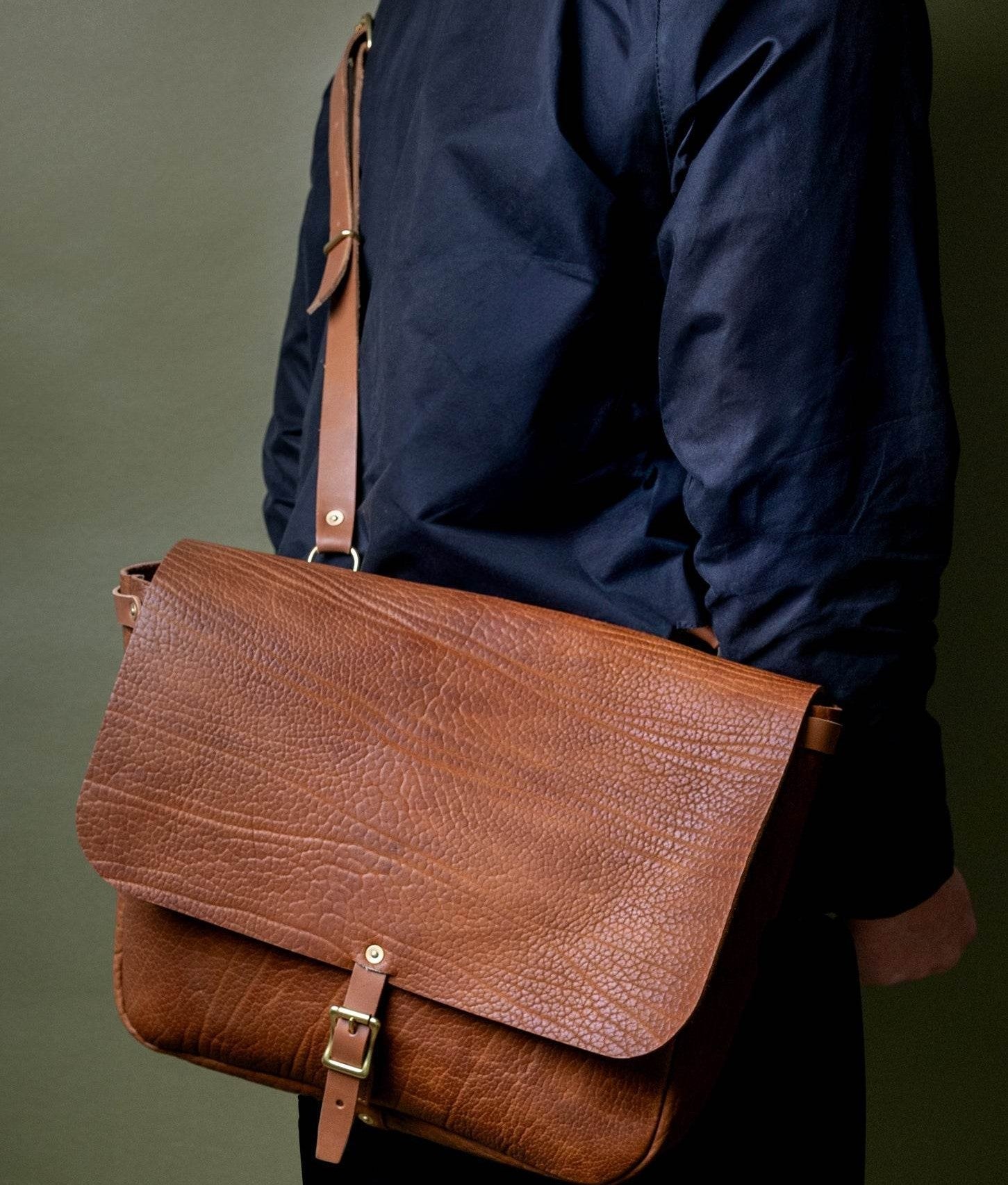  A Leather Messenger Bag from WP Standard with a long, luxurious strap on the shoulder of a model. 