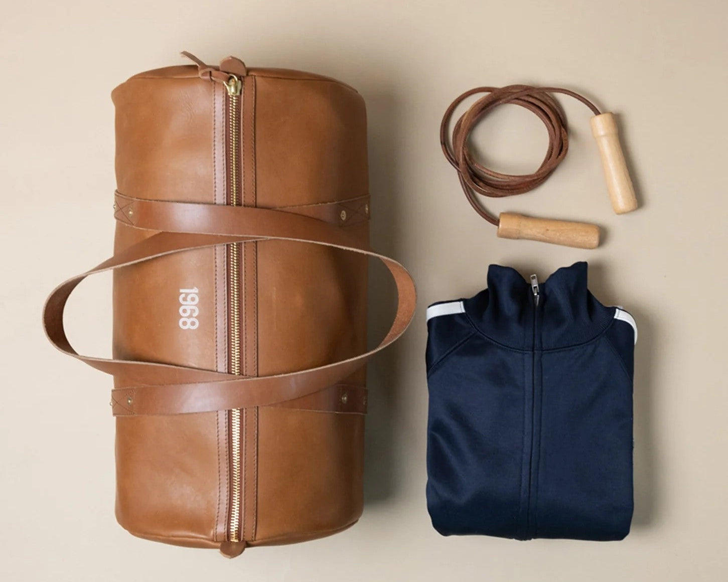 A brown leather 1968 gym bag from WP Standard, a navy blue jacket, and a jump rope.
