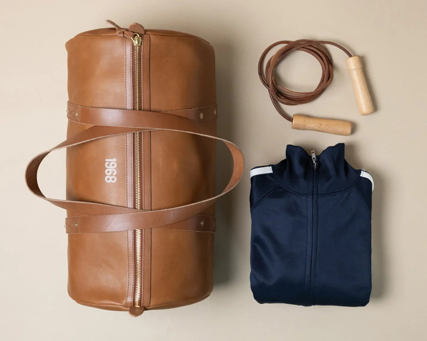 A brown leather 1968 gym bag from WP Standard, a navy blue jacket, and a jump rope.