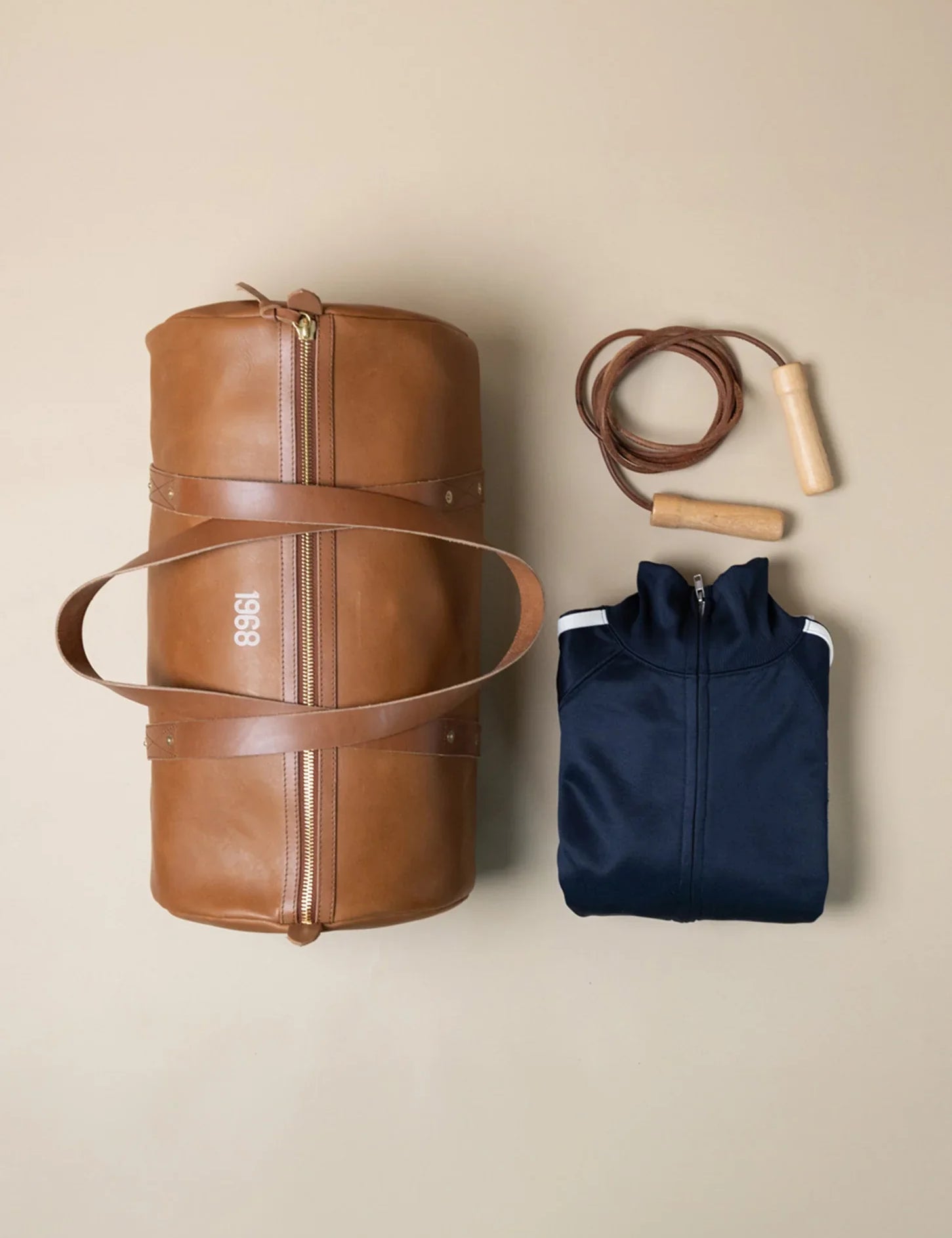 A brown leather 1968 gym bag from WP Standard, a navy blue jacket, and a jump rope.