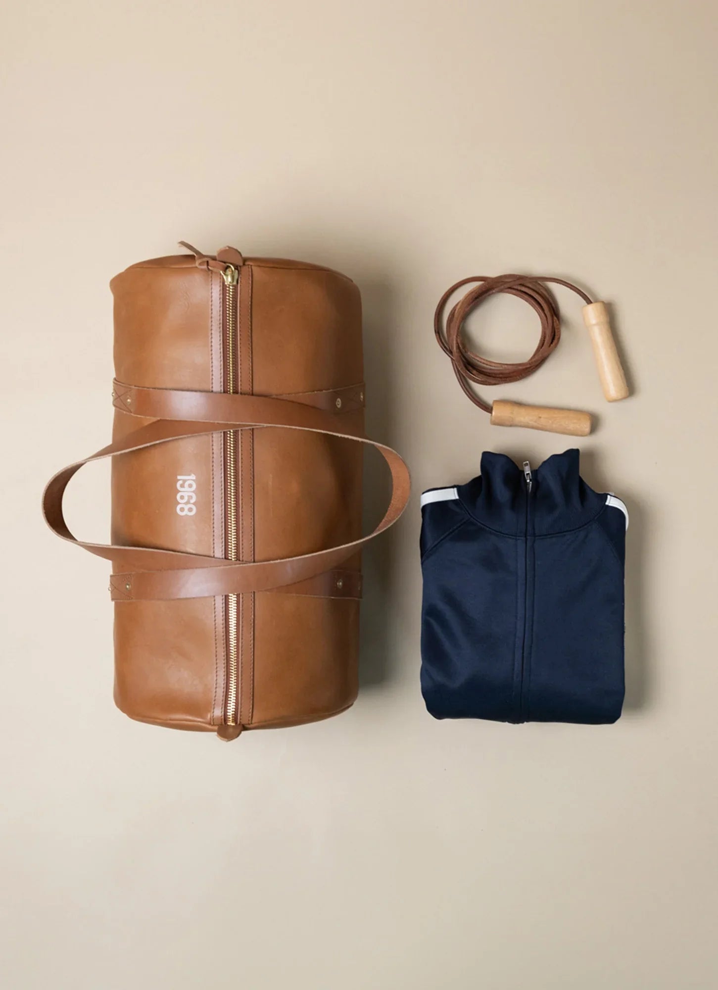 A brown leather 1968 gym bag from WP Standard, a navy blue jacket, and a jump rope.