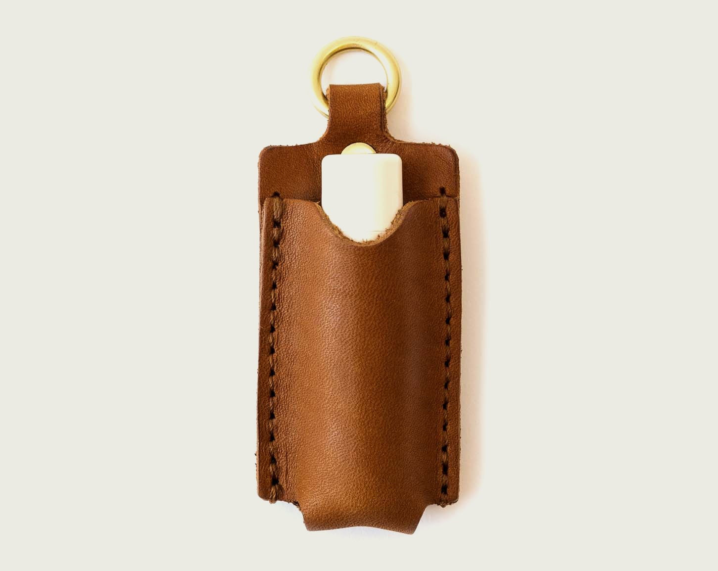 A product shot of the WP Standard lip balm holder in tan color with a brass attachment.