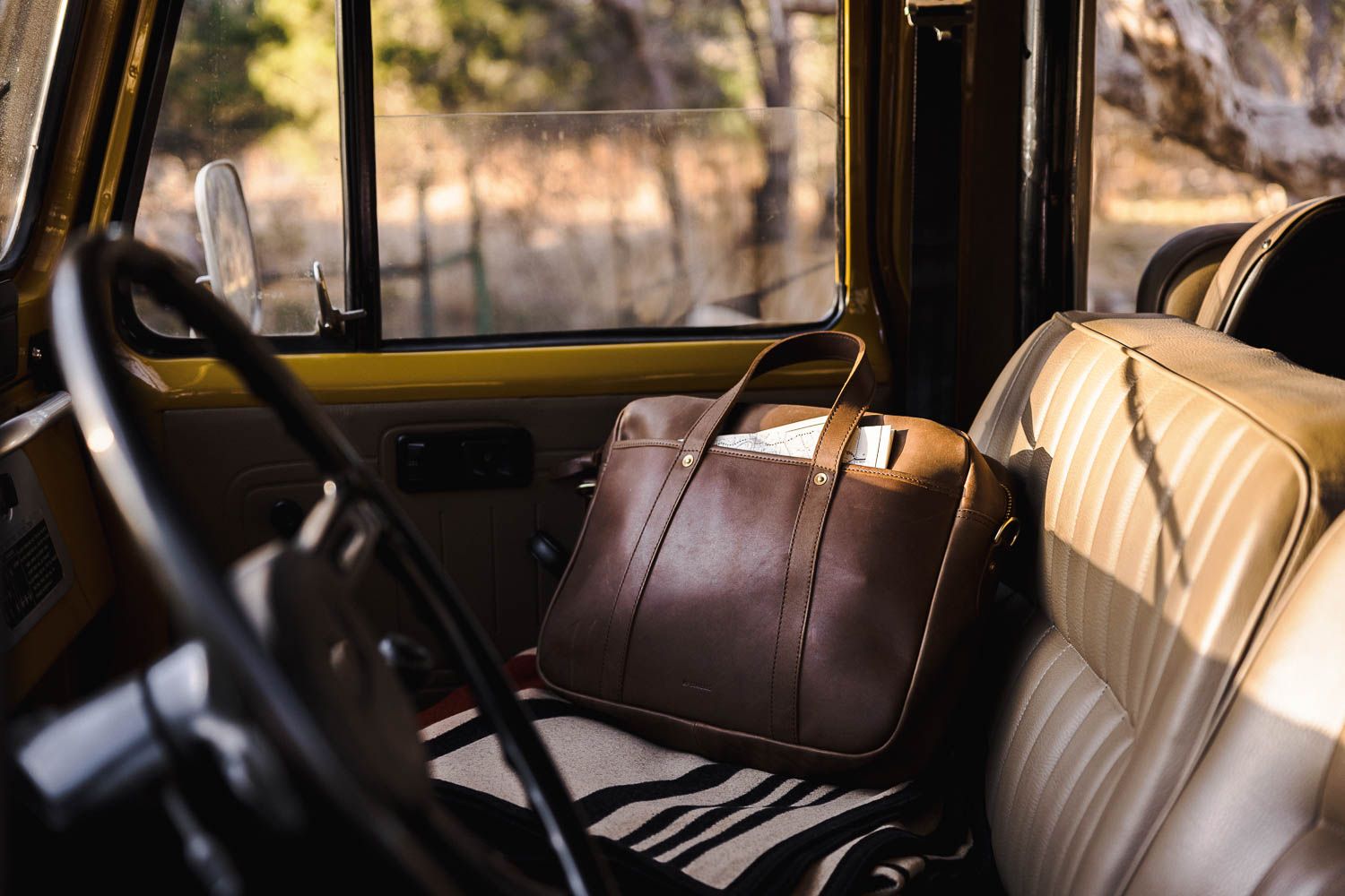 Leather travel messenger bag on a vintage car seat, showcasing luxury and utility in 2025 corporate gifting.