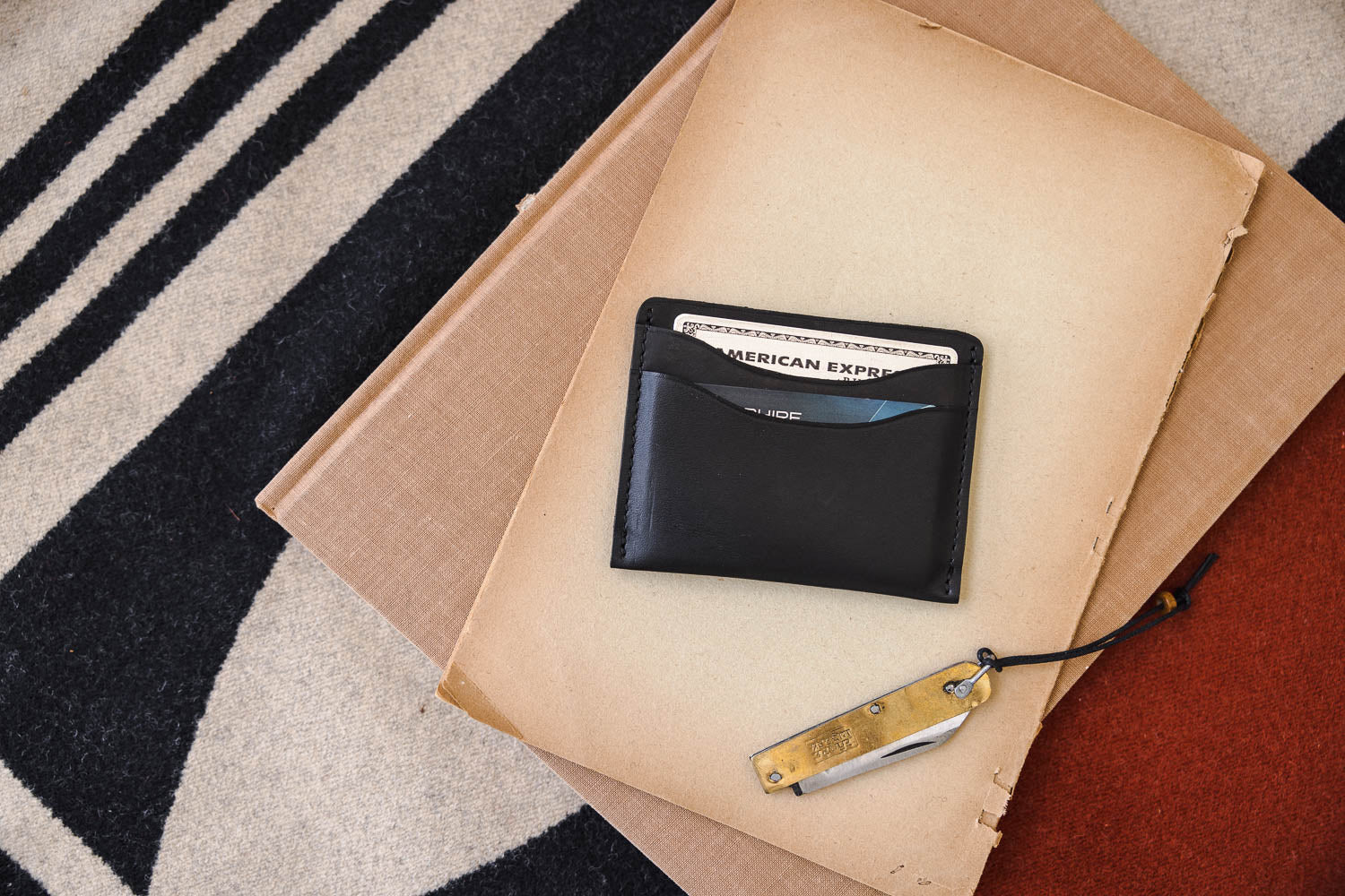 A small black leather wallet from WP Standard placed on a rug. 