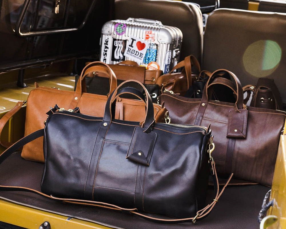 Vibrant weekender bags in assorted colors lined up on a bus doorstep, ready for stylish weekend travel.
