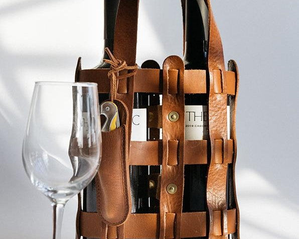 A wine tote bag from WP Standard, along with a wine glass against a white background.