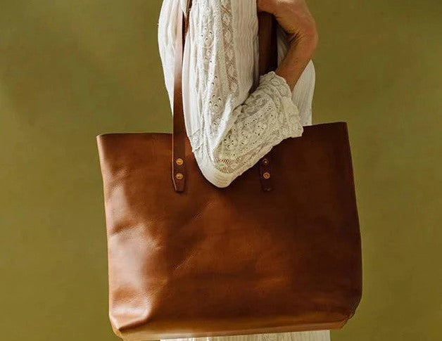 A woman holding a brown leather tote bag