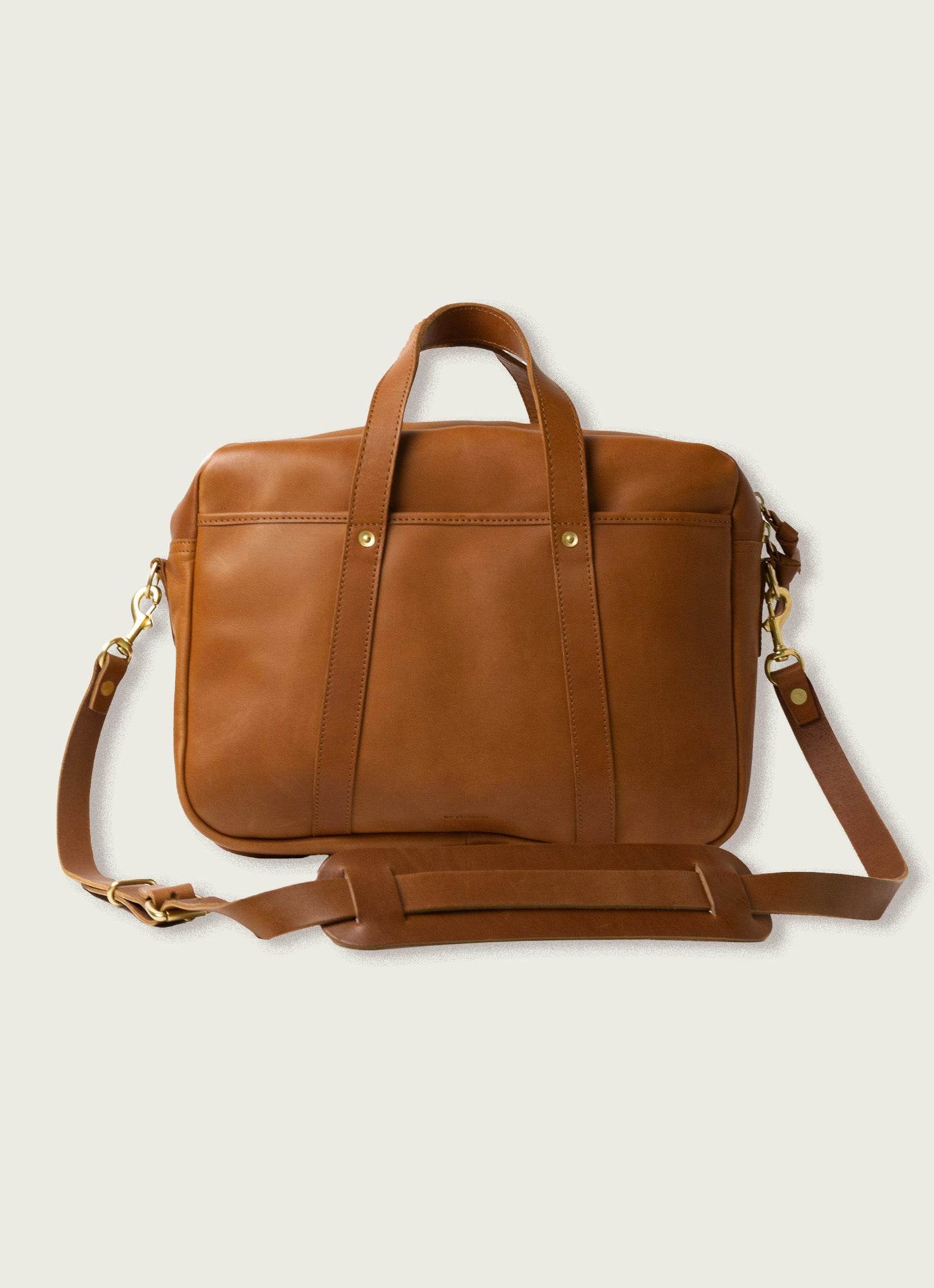 A sleek tan leather messenger bag with top handles and an adjustable shoulder strap, designed for minimalist style and functionality.