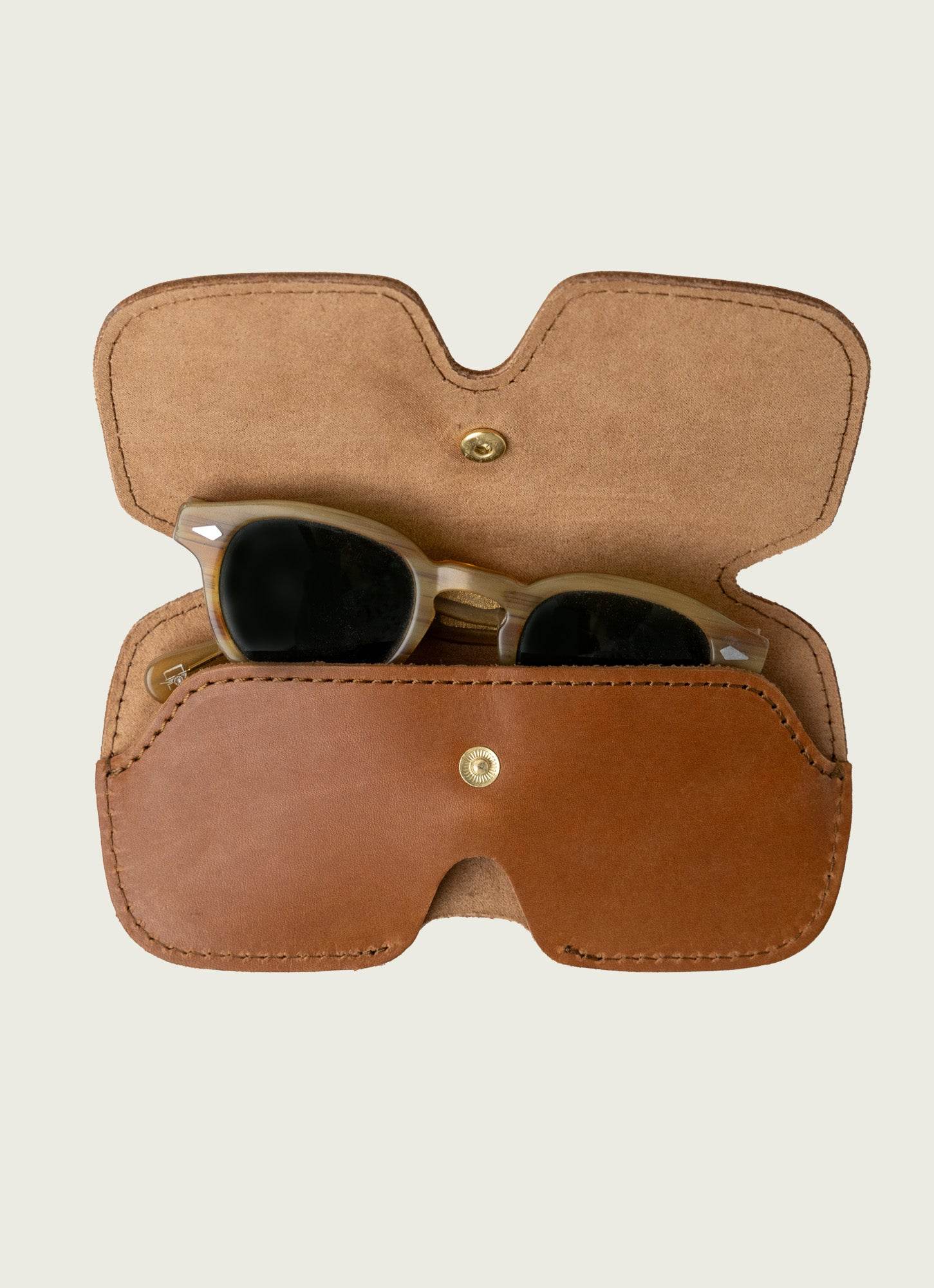 Leather sunglass case with brass snap closure, protecting stylish sunglasses with a personalized corporate gift appeal.