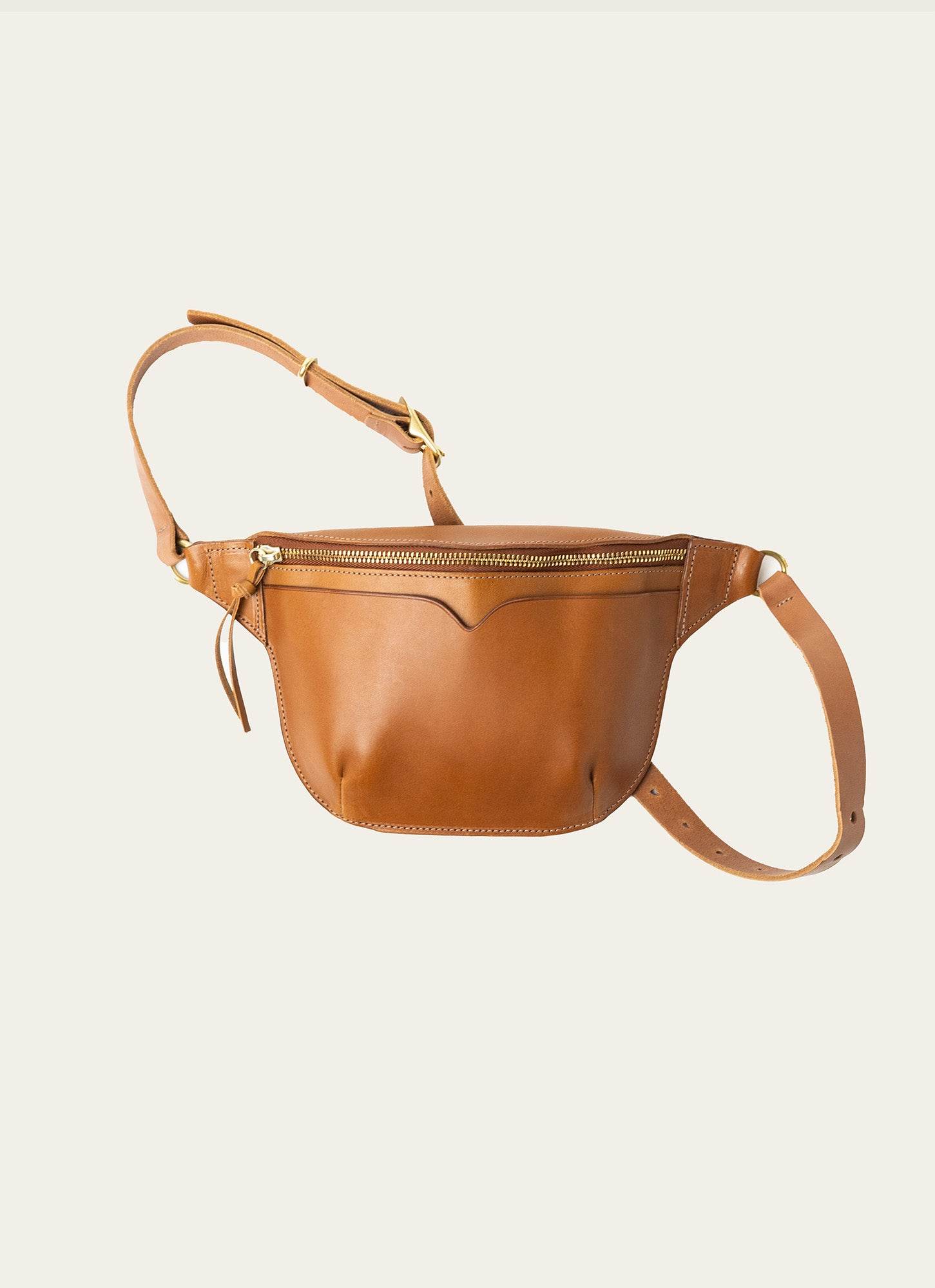 Minimalist leather sling bag with magnetic flap and adjustable strap.