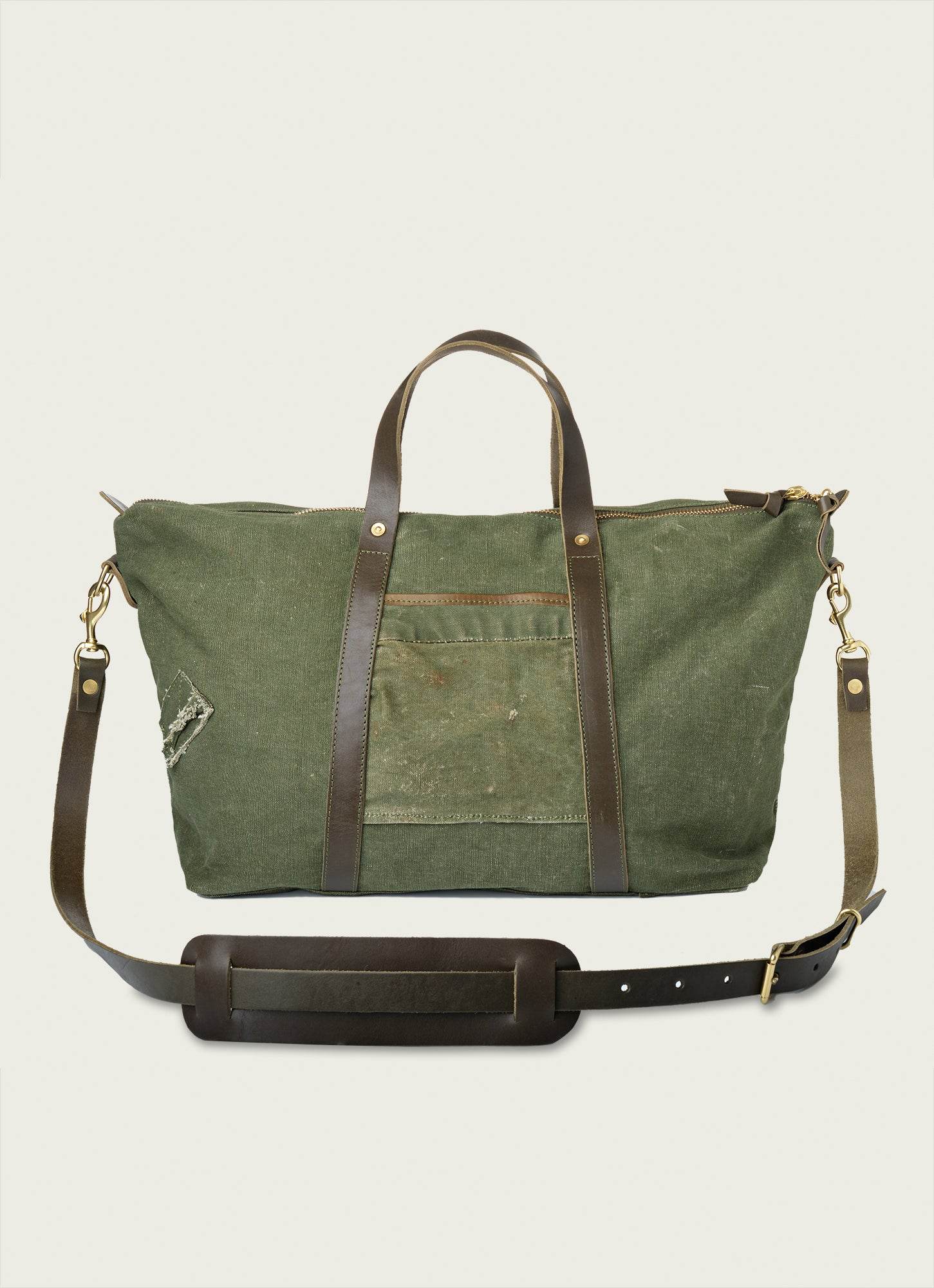 Rugged repurposed military canvas and full-grain leather travel tote with sturdy handles and vintage style.